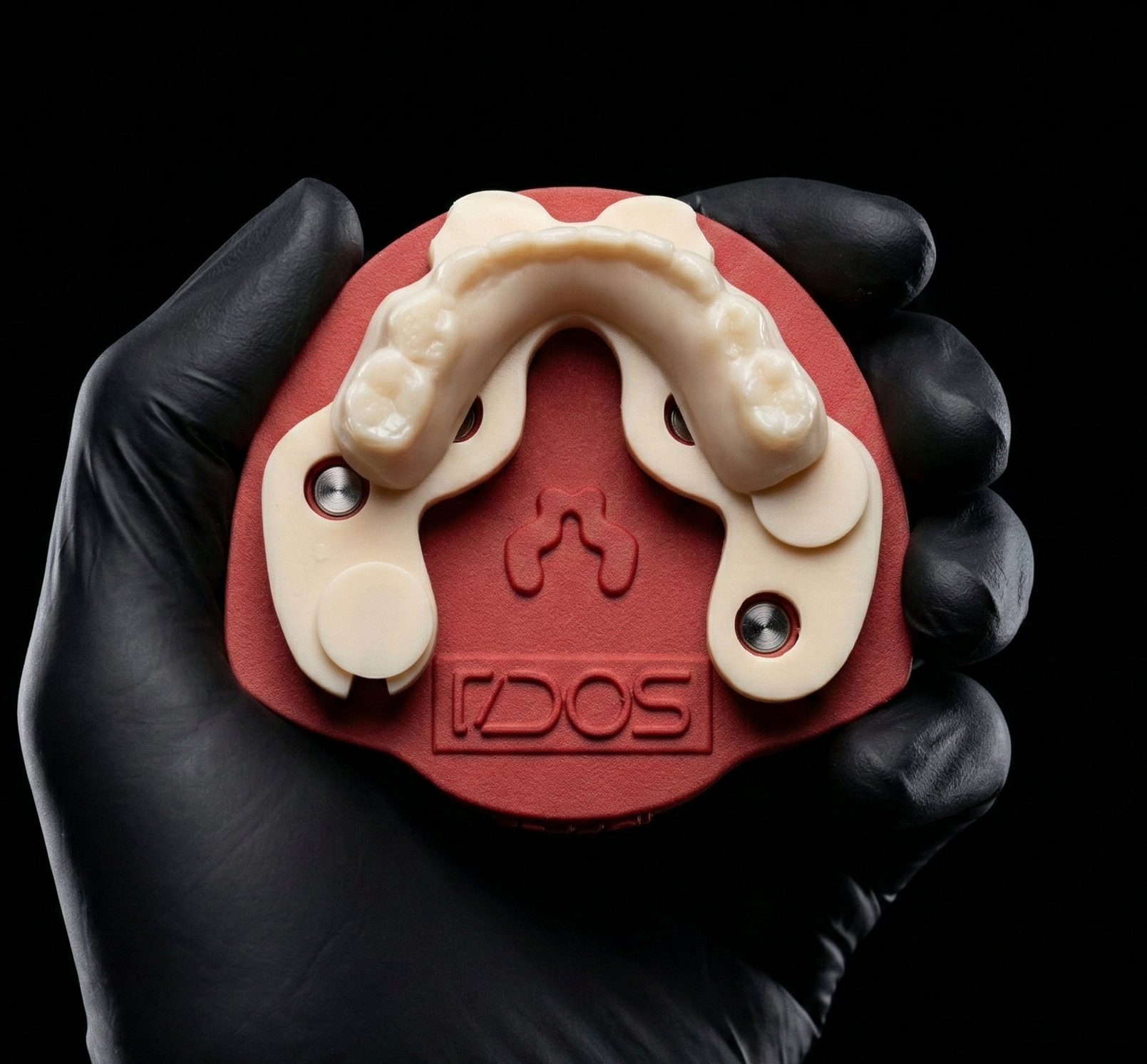 A full-arch posterior case seated on a Light plate, held in a gloved hand on a black background.